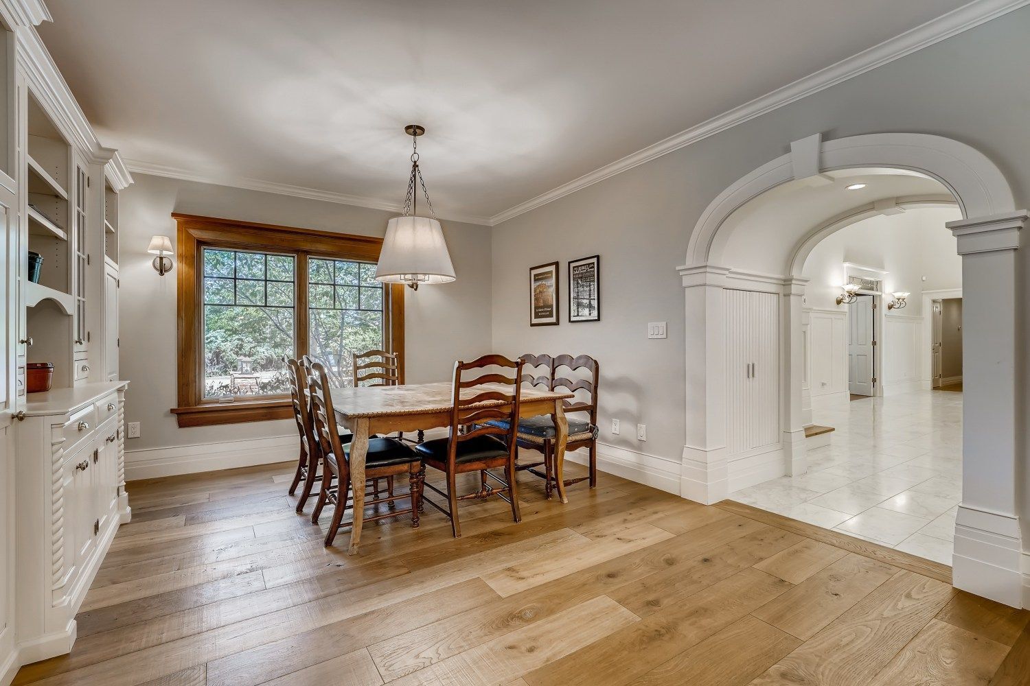 A dining room with a table and chairs and a large window.