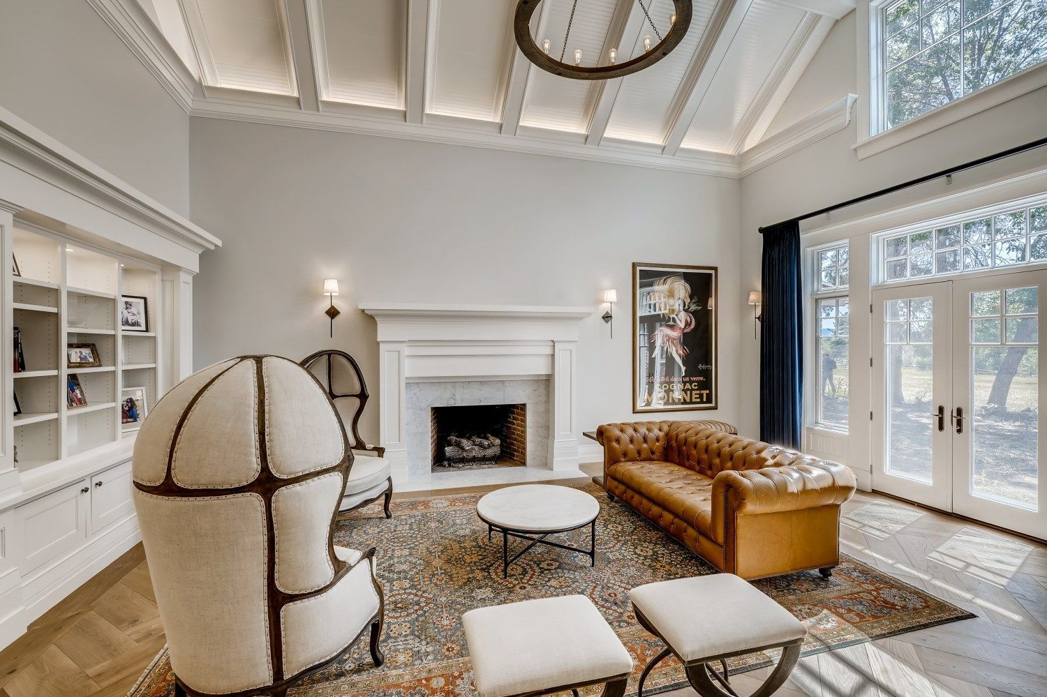 A living room with a couch, chairs, ottomans, and a fireplace.
