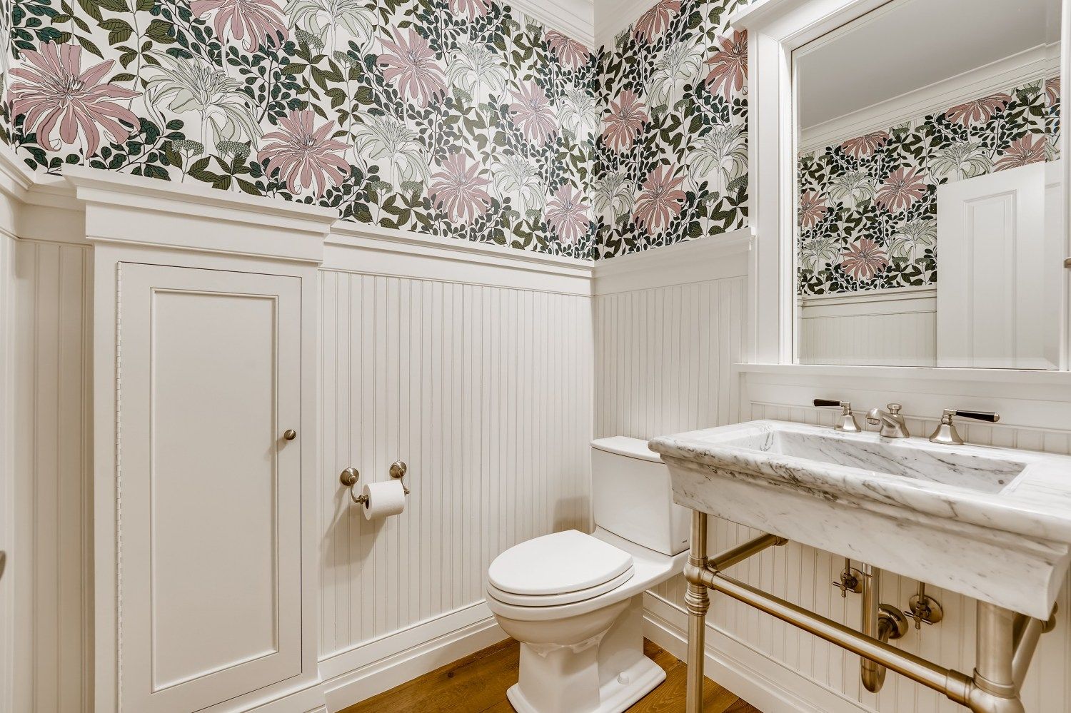 A bathroom with a toilet, sink, and mirror.