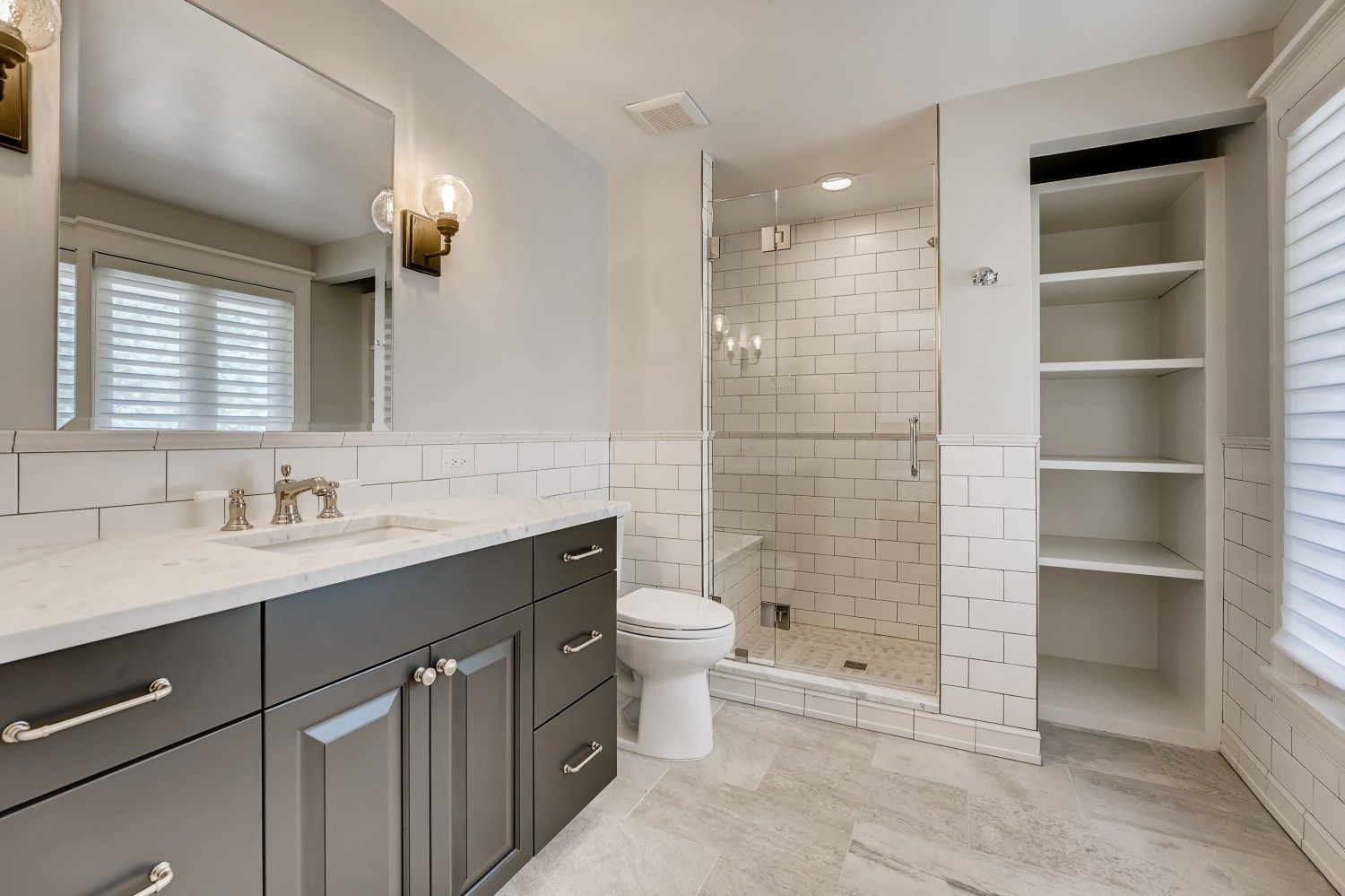 A bathroom with a toilet, sink, mirror, and walk in shower.