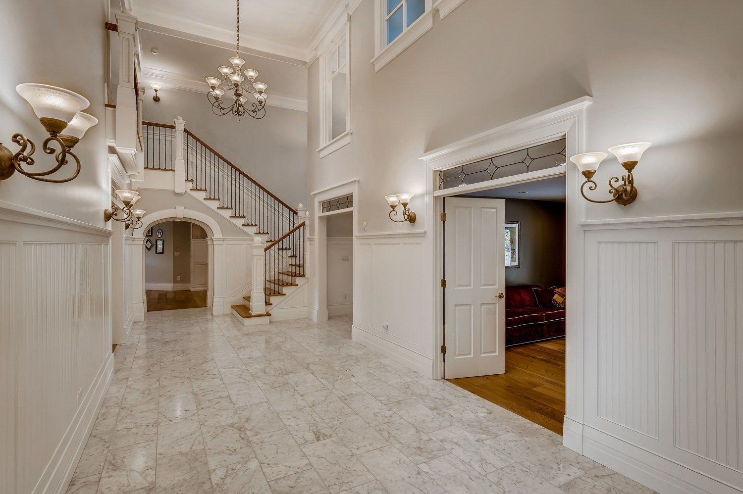 A large hallway with stairs and a chandelier in a house.