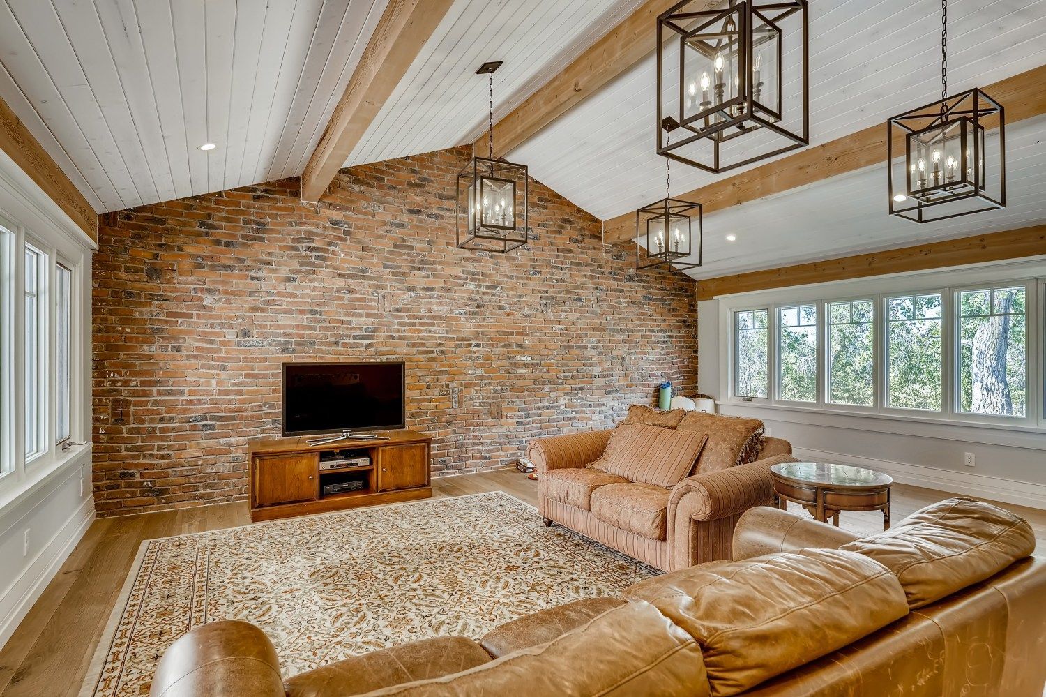 A living room with a brick wall, a couch, a television, and a rug.