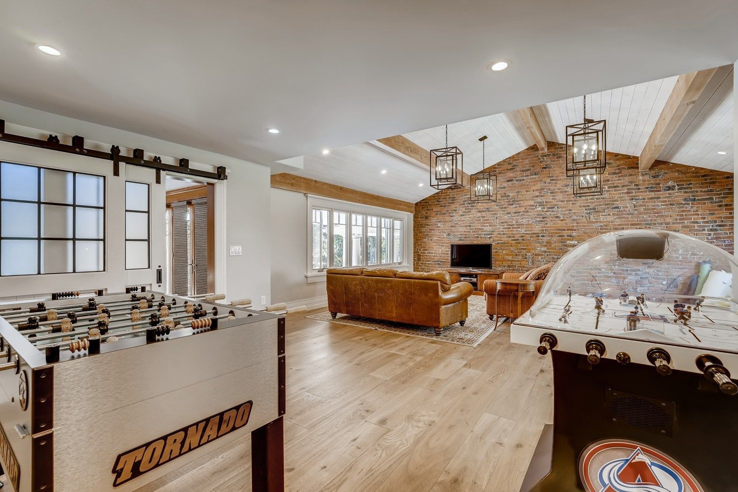 A living room with a foosball table and a brick wall.