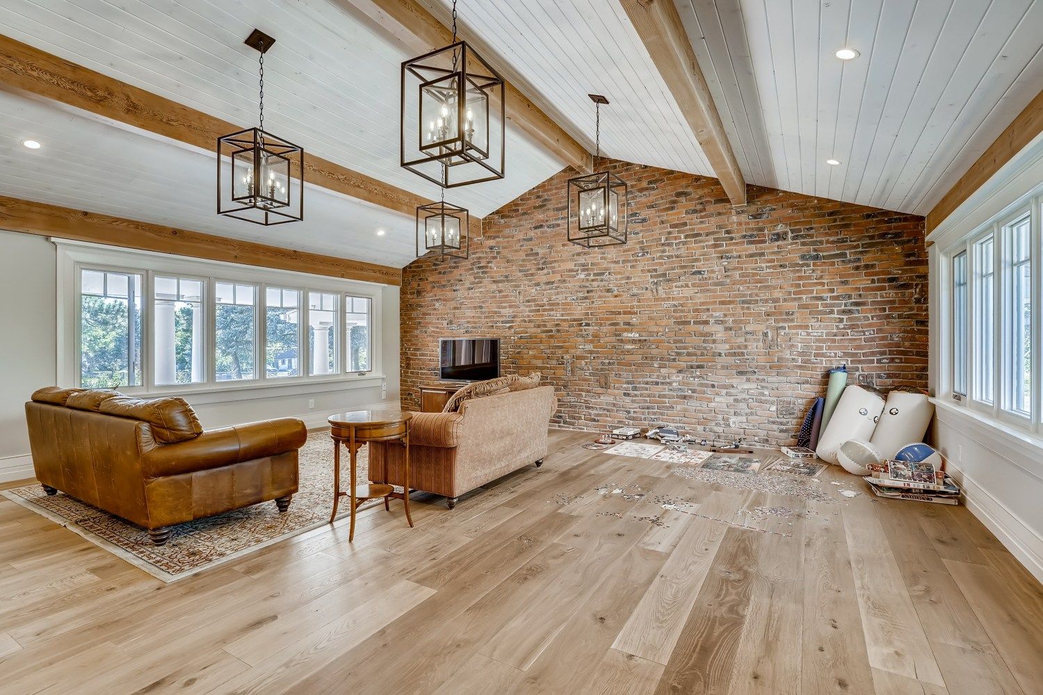 A living room with hardwood floors and a brick wall.
