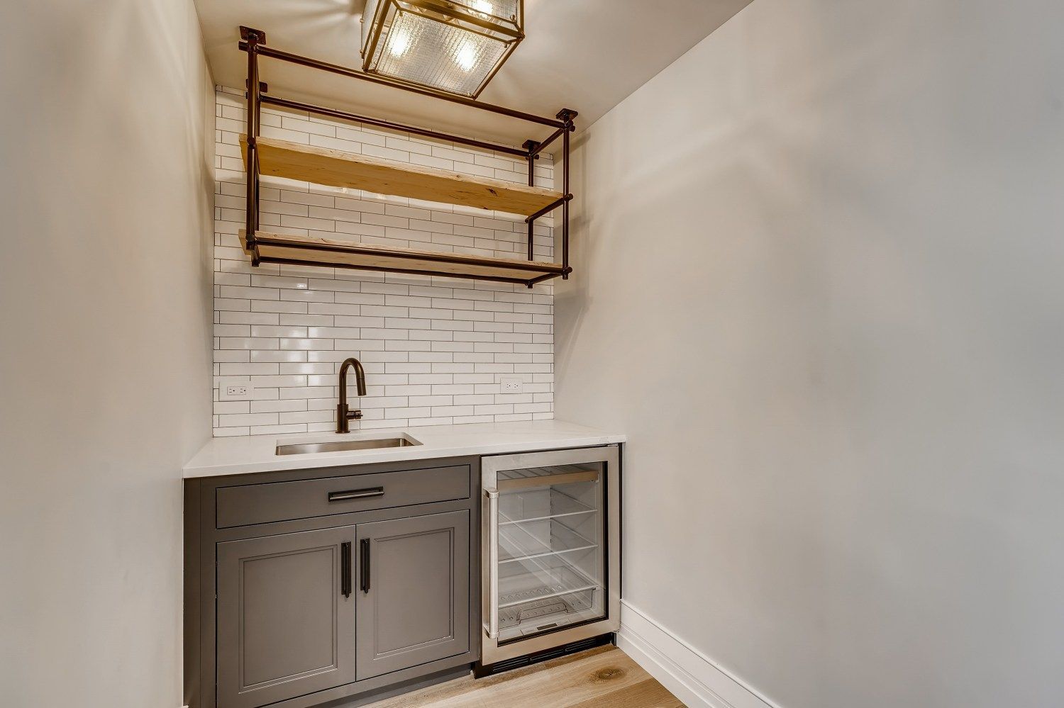 A kitchen with a sink, refrigerator, and shelves.