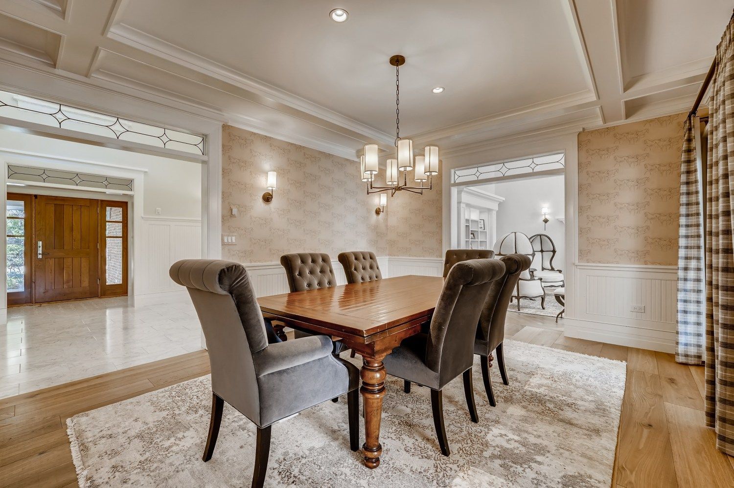 A large kitchen with white cabinets, black counter tops, stainless steel appliances, and hardwood floors.