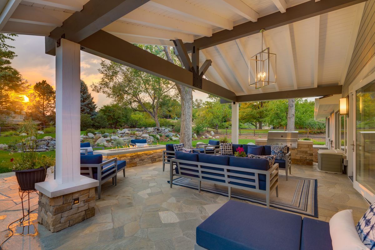 A large covered patio with a lot of furniture and a sunset in the background.