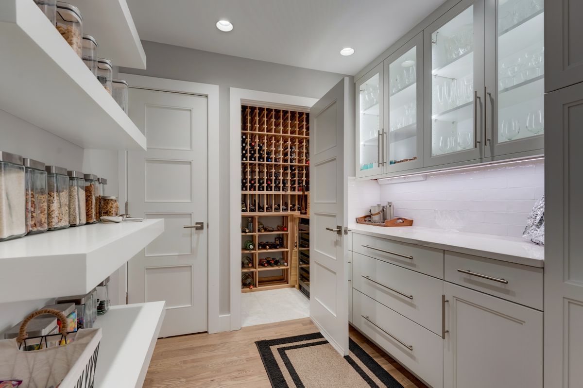 A kitchen with white cabinets and a wine cellar.