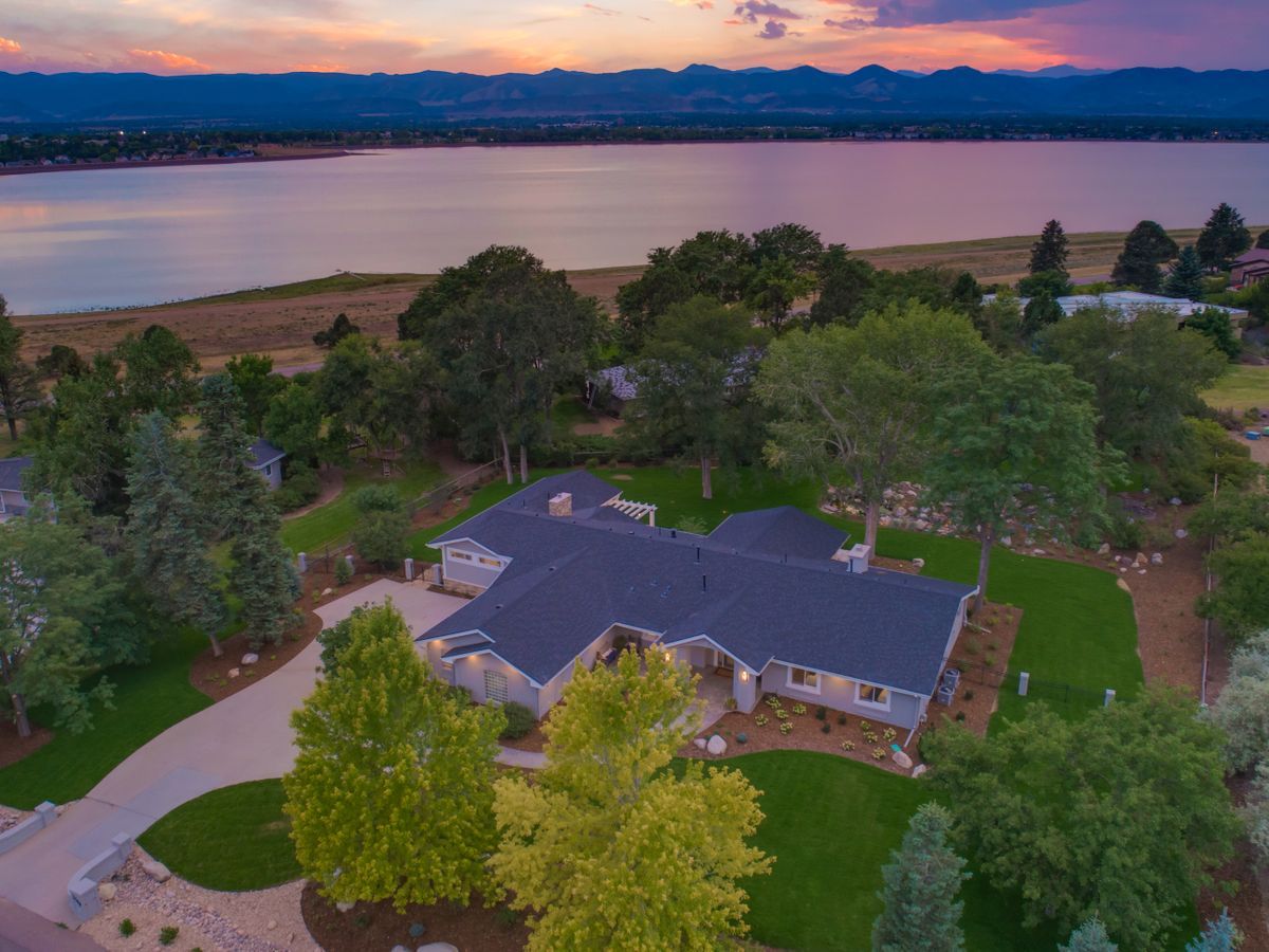 An aerial view of a house next to a lake at sunset.
