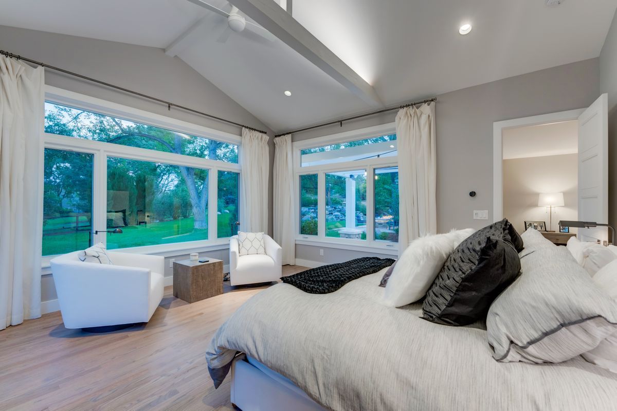 There is a large bed in the middle of the room with a lot of windows.