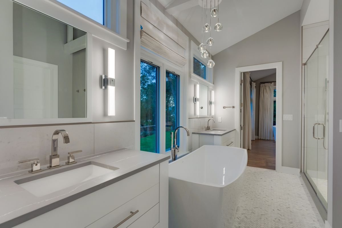 A bathroom with a tub, sink, and mirrors.