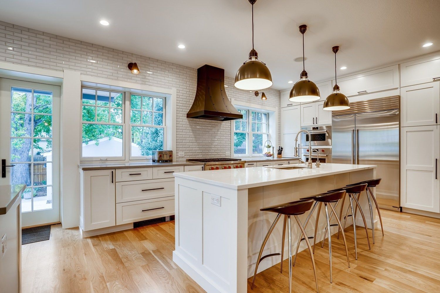 A kitchen with a large island, stools, and a stove.
