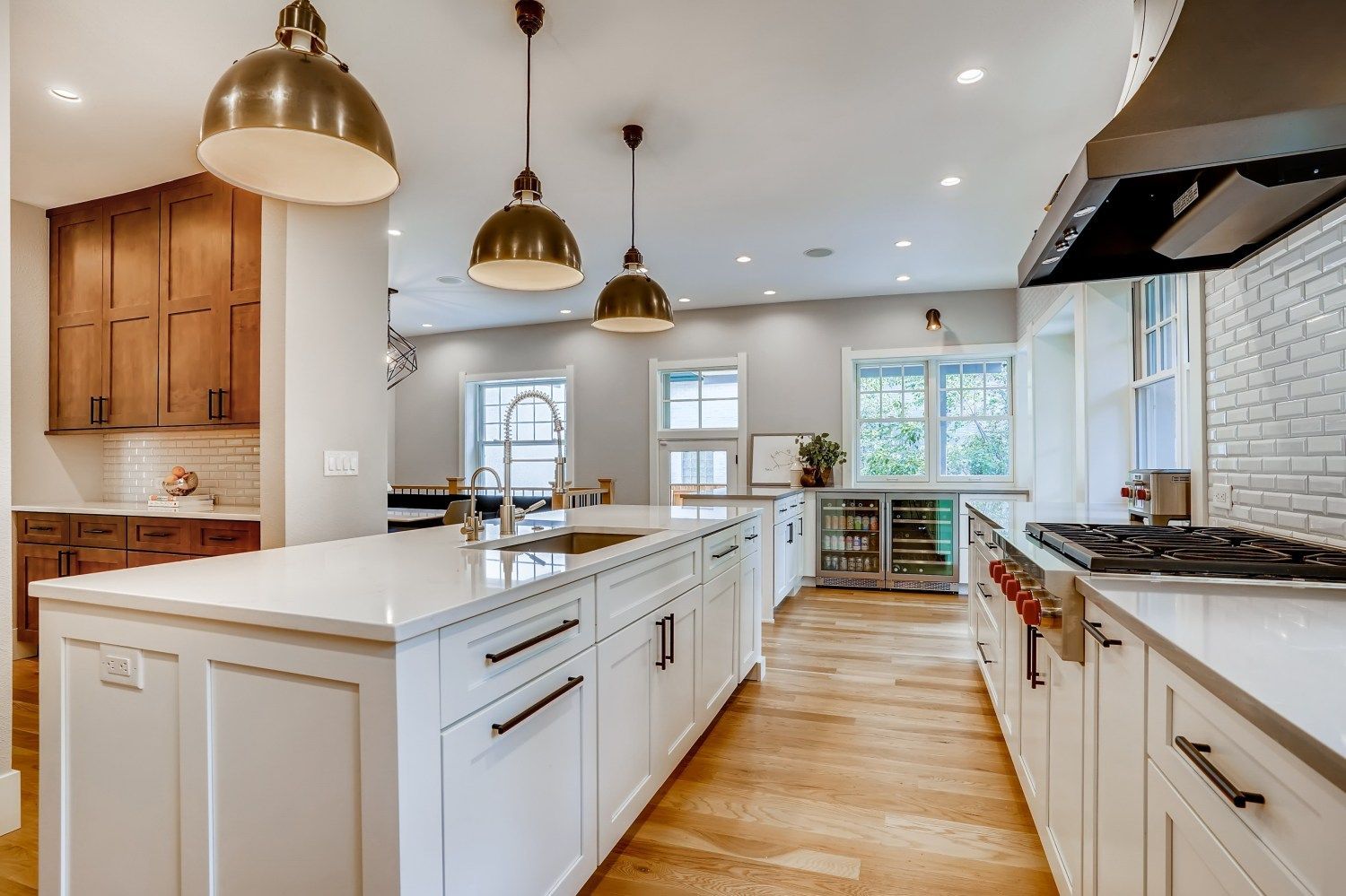 A kitchen with white cabinets and wooden floors and a large island in the middle.