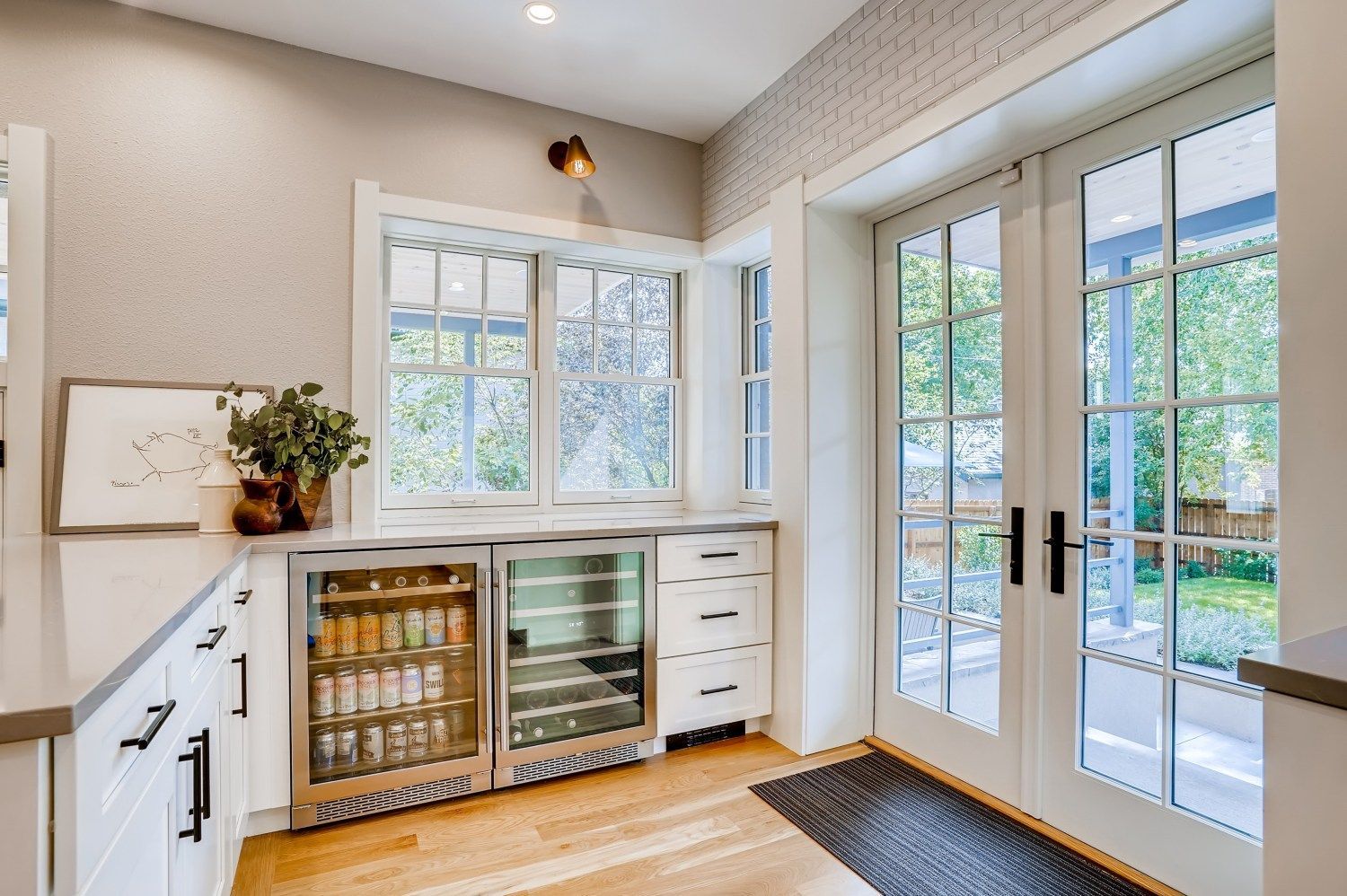 A kitchen with a wine cooler and french doors.