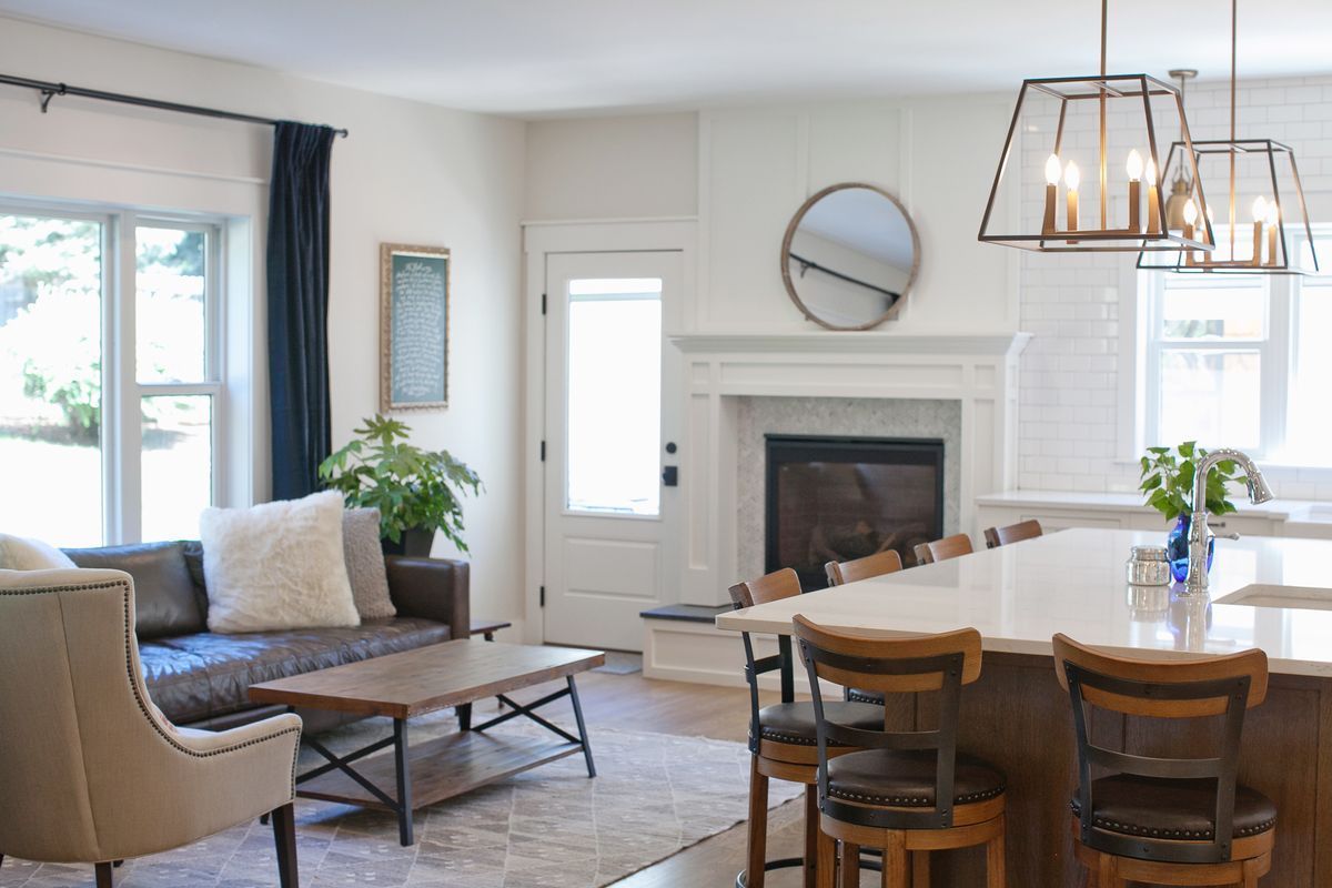 A living room with a couch, chairs, table, and fireplace.