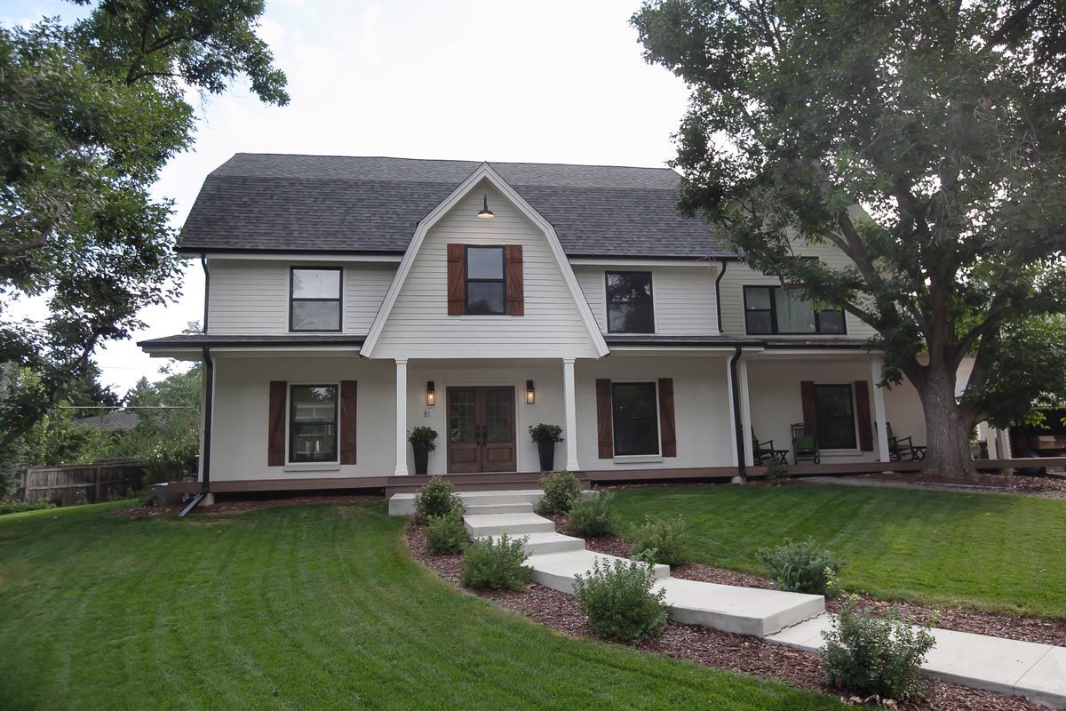 A large white house with a gray roof and a porch.