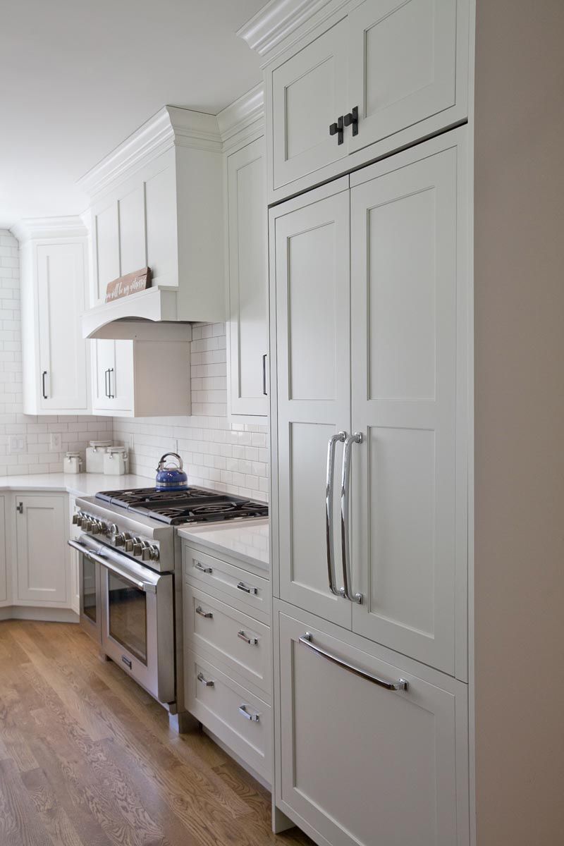 A kitchen with white cabinets, a stove, and a refrigerator.