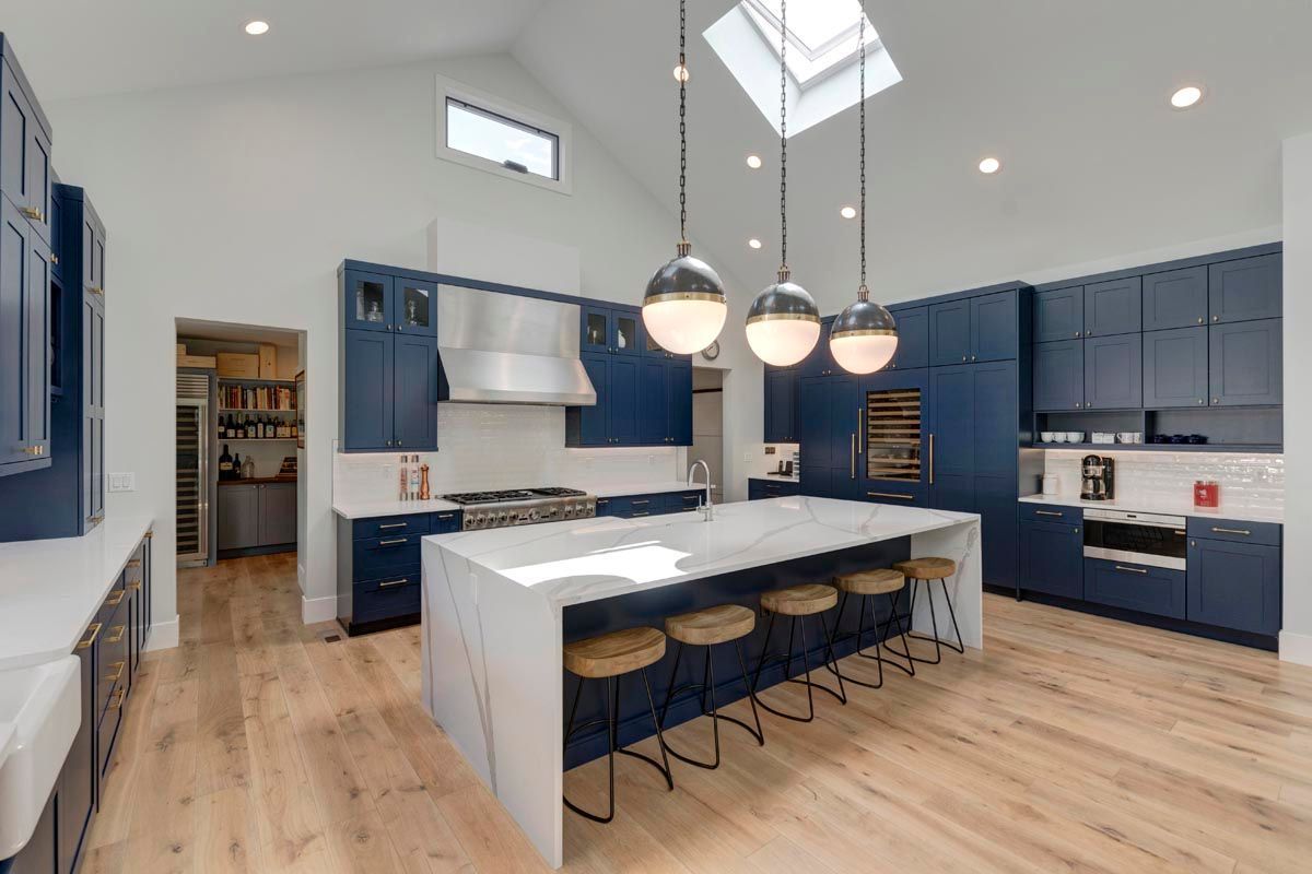 A kitchen with blue cabinets, white counter tops, and a large island.