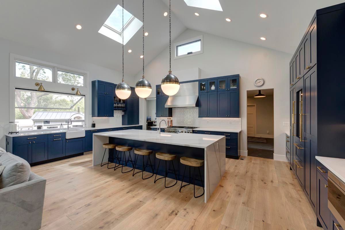A kitchen with blue cabinets and a large island in the middle.
