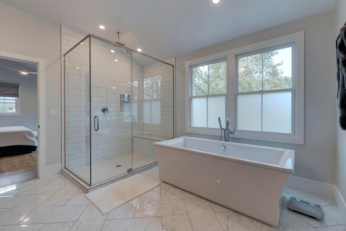 A bathroom with a tub, shower, and window.