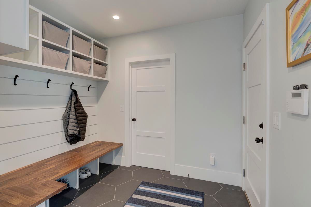 A mud room with a bench and hooks on the wall.