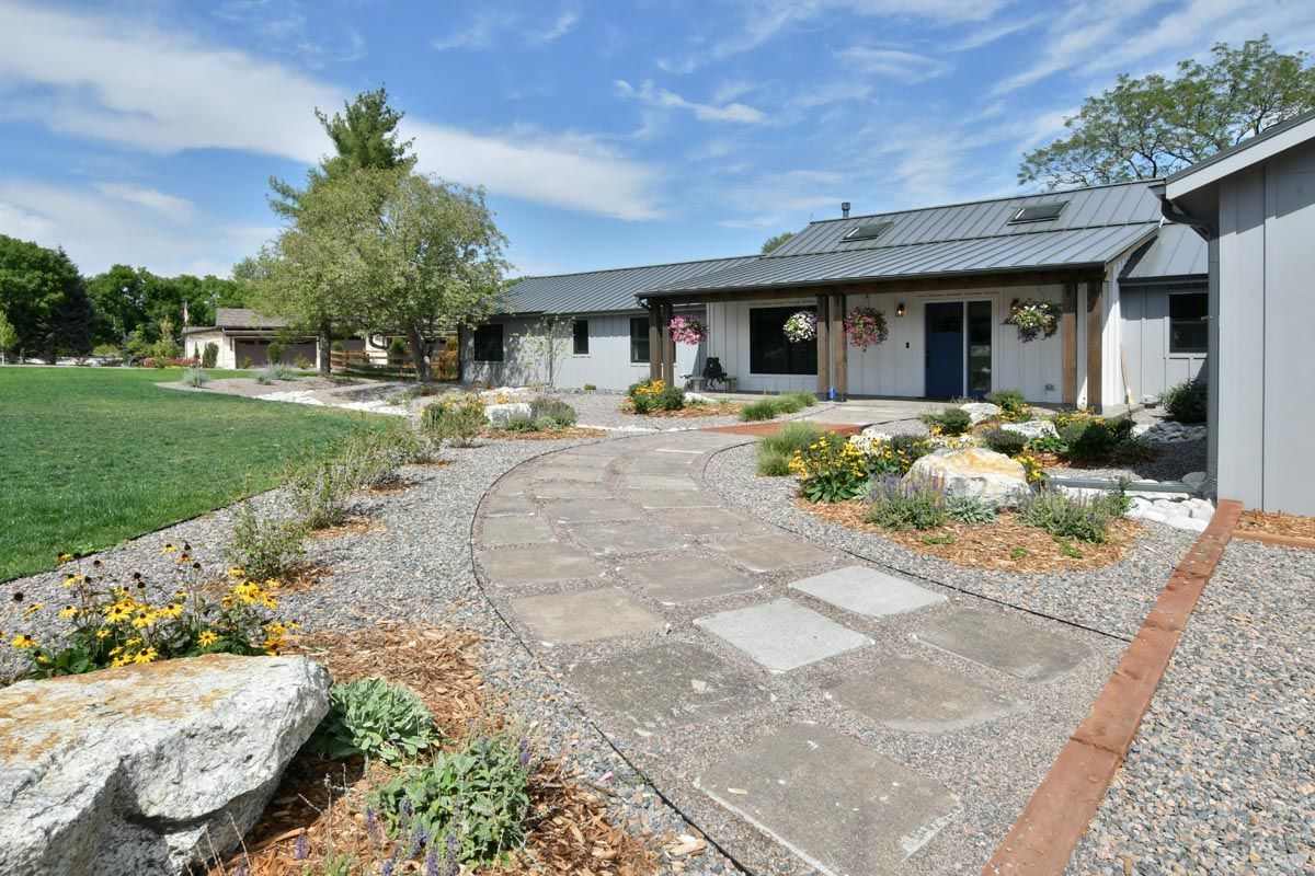 A concrete walkway leading to a house with a shed in the background.
