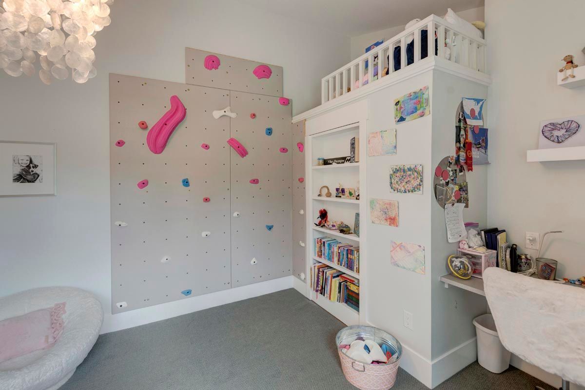 A bedroom with a bed, desk, couch, and window.