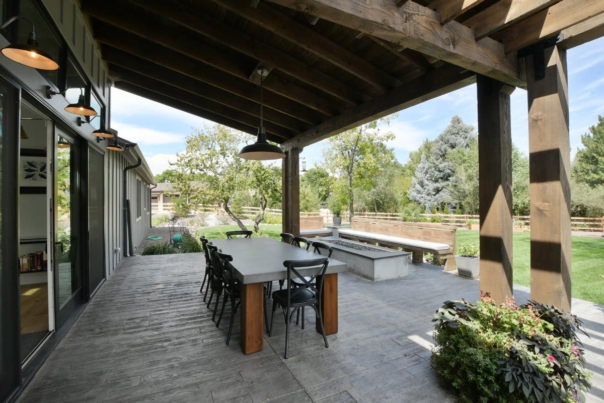 A large patio with a table and chairs under a pergola.