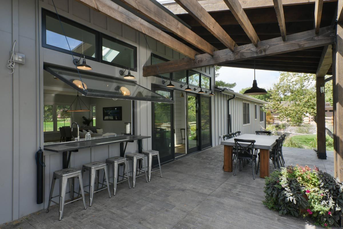 A patio with a table and stools under a pergola