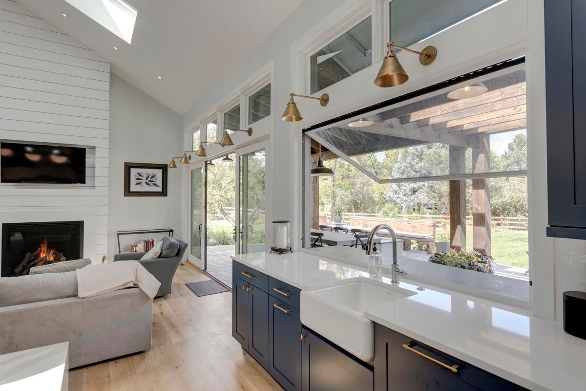 A kitchen with a sink, dishwasher, and sliding glass doors leading to a living room.
