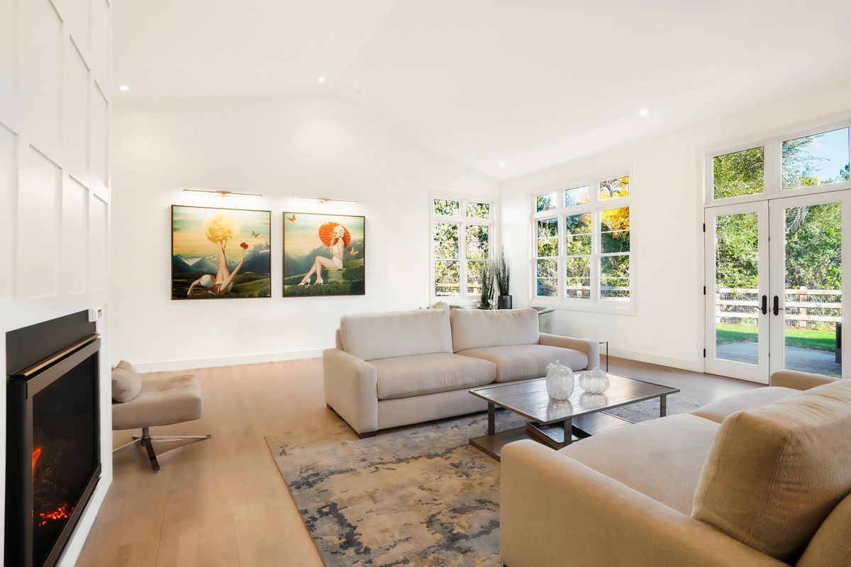 A living room with a white couch, coffee table, fireplace, and paintings on the wall.