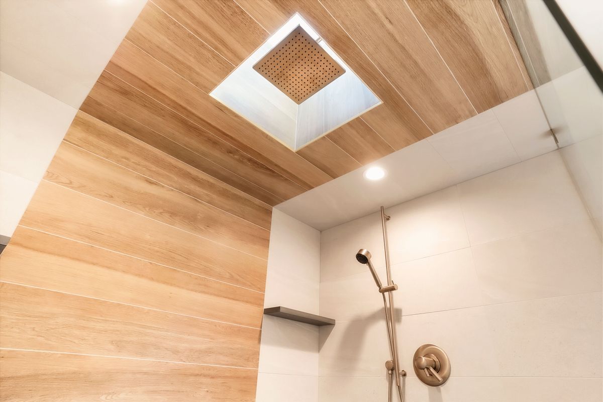 A bathroom with a wooden ceiling and a shower head.