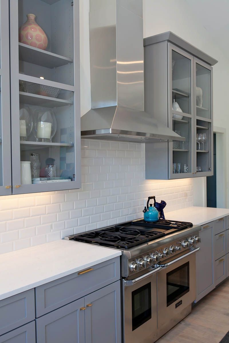 A kitchen with stainless steel appliances and gray cabinets.