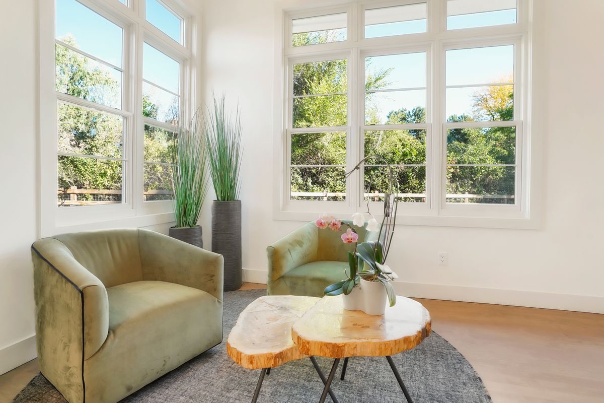 A living room with a couch, chair, table, and windows.