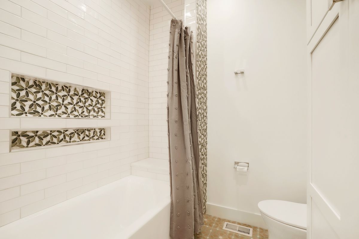 A bathroom with a tub, toilet, and shower.