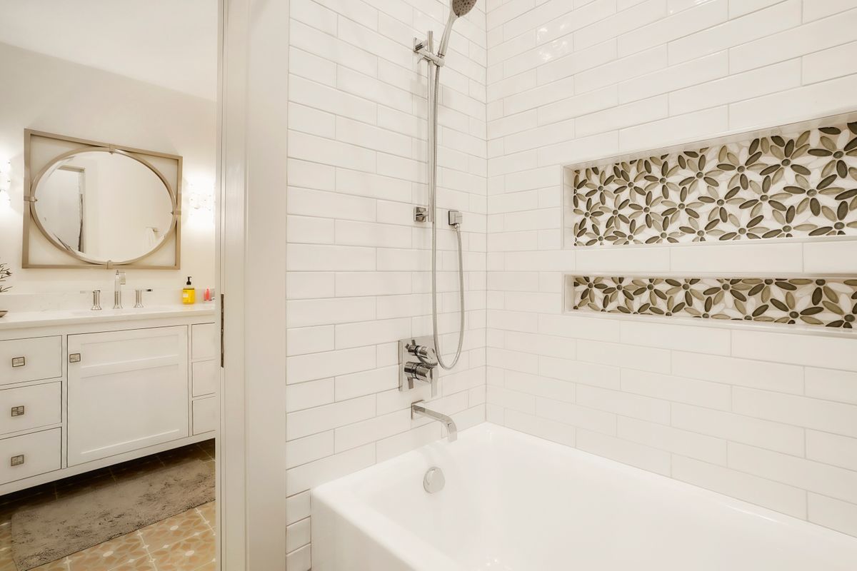 A bathroom with a bathtub, sink, mirror, and shower.