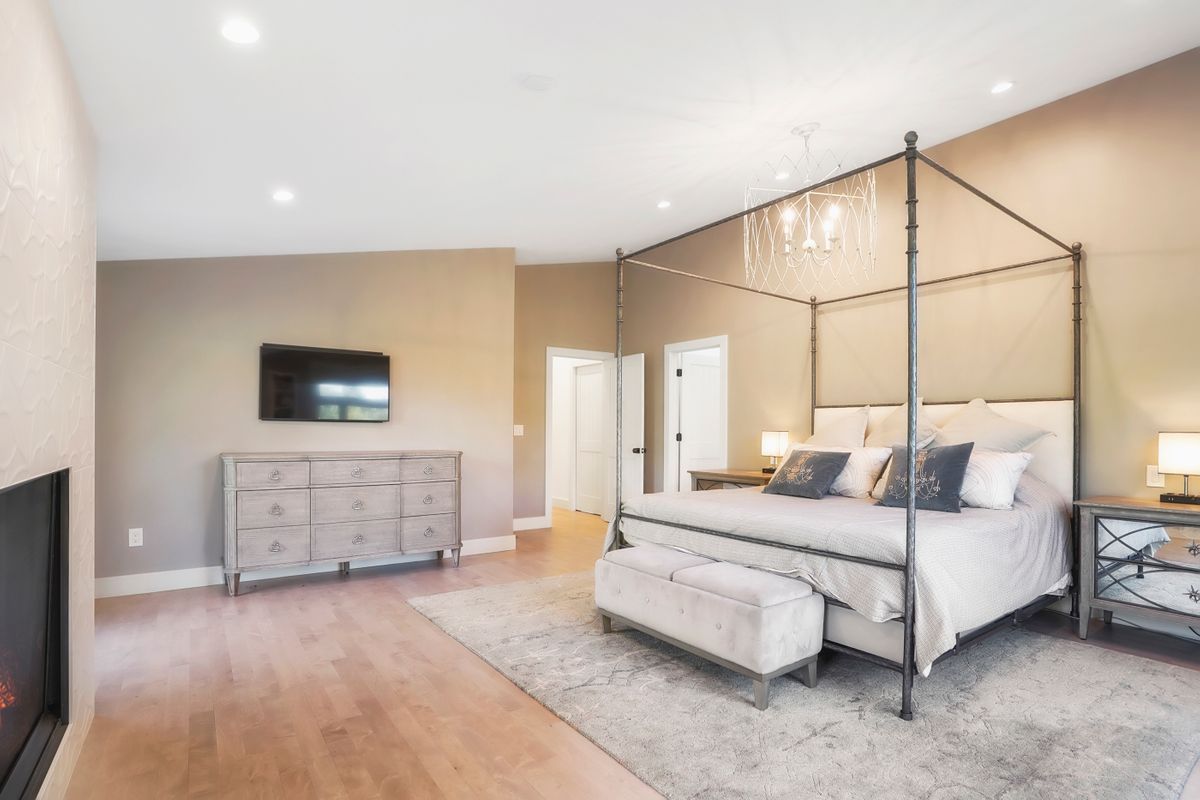 A bedroom with a canopy bed and a fireplace.