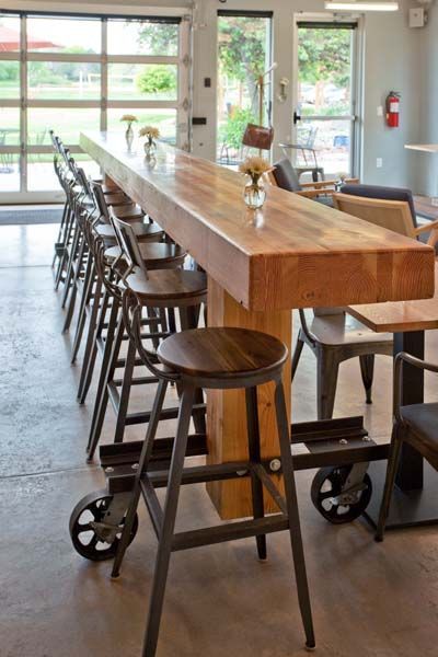 A long wooden table with a lot of stools around it.