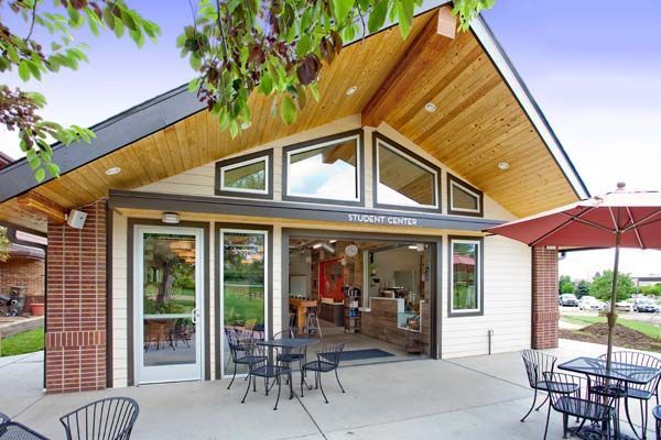 The outside of a building with tables and chairs and umbrellas.