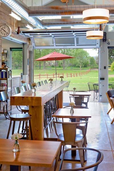 A restaurant with tables and chairs and a red umbrella.