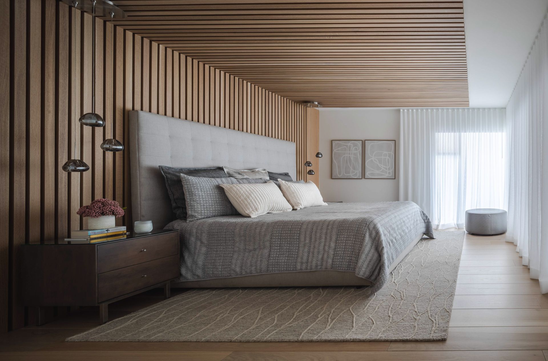 A bedroom with a bed , nightstand , rug and wooden walls.