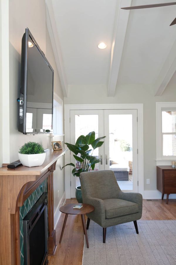 A living room with a fireplace, chair, table, and television.