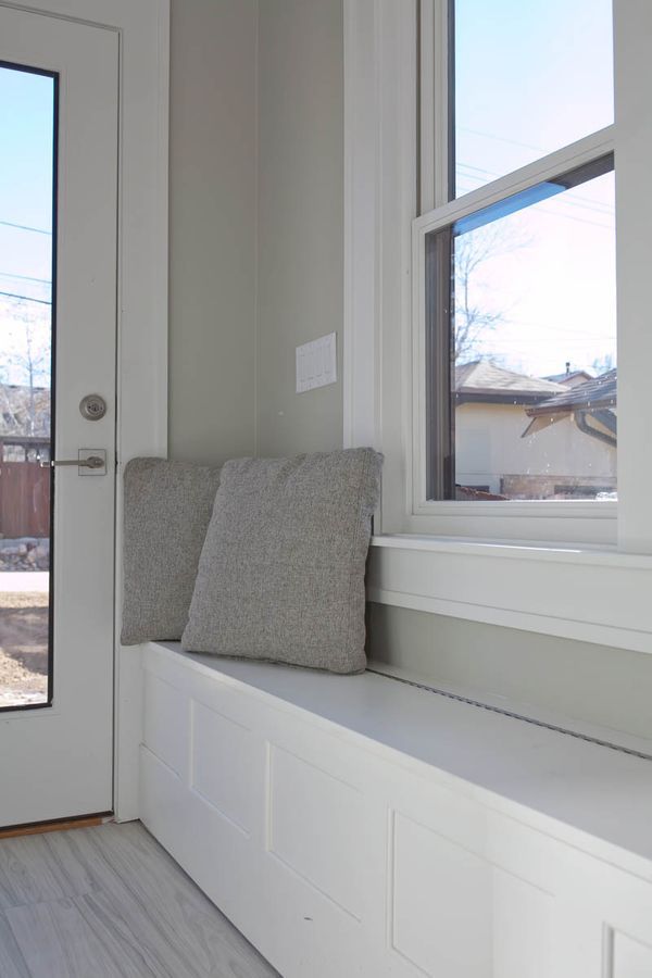 A window seat with two pillows in front of a door.