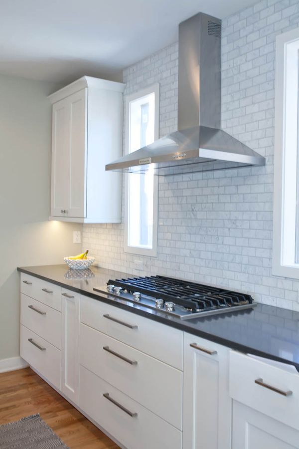 A kitchen with white cabinets and a stove top oven.