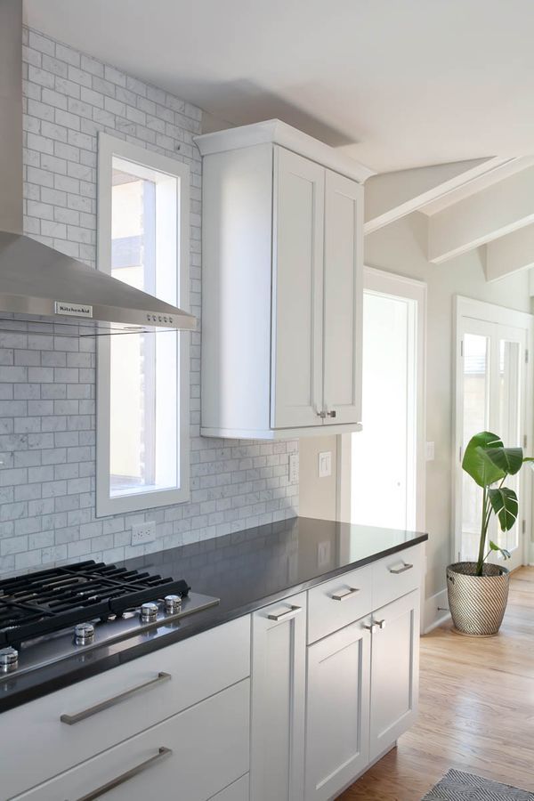 A kitchen with white cabinets, black counter tops, and a stove top oven.
