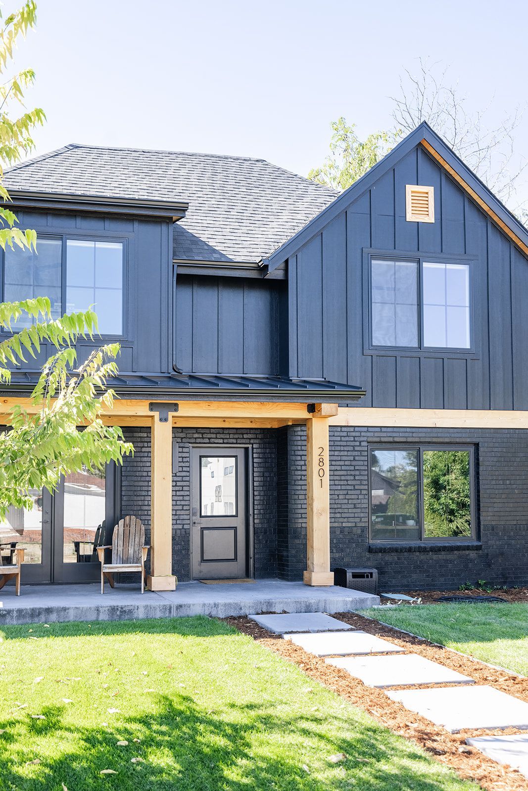 A black house with a wooden porch and a chair in front of it.