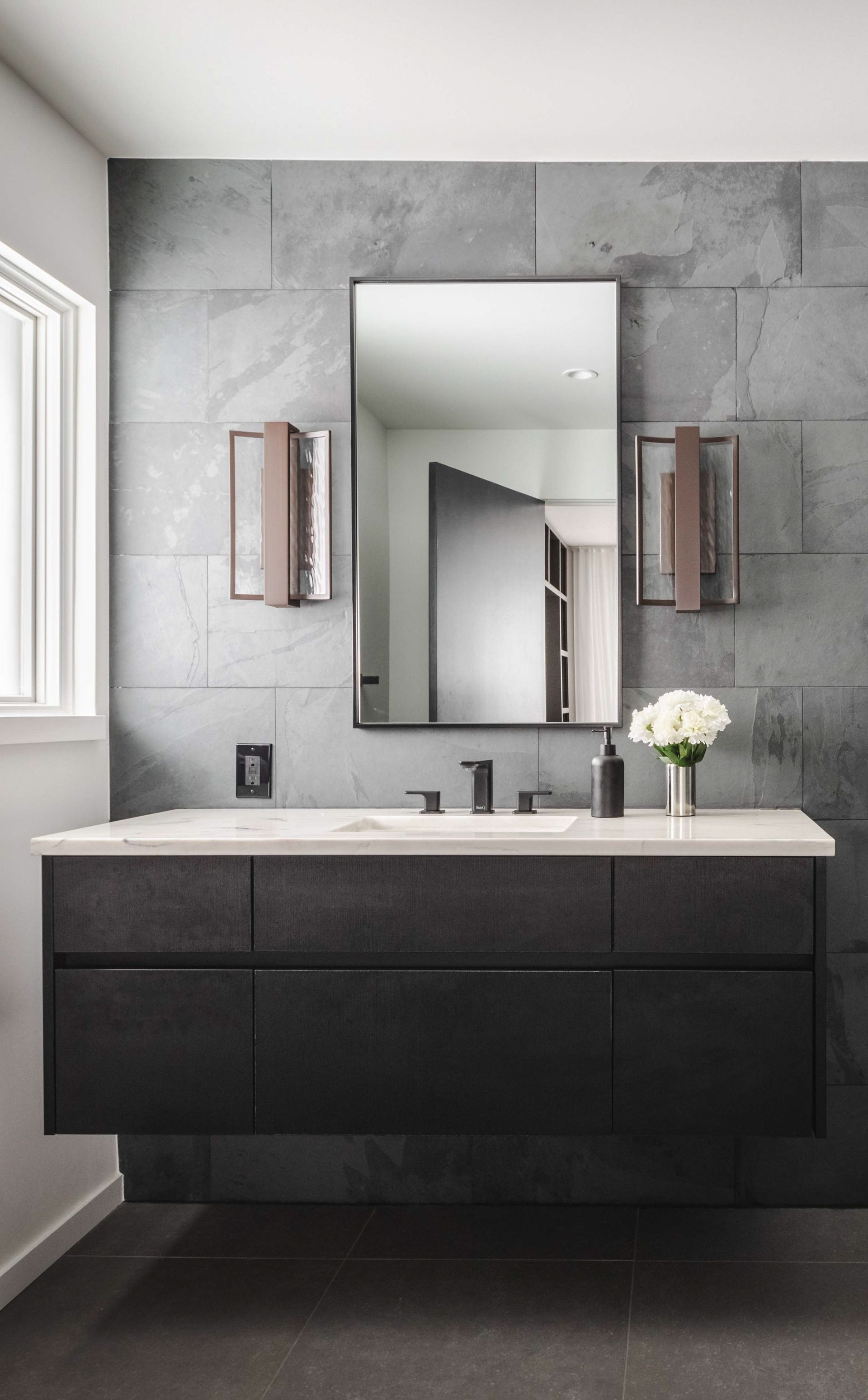 A bathroom with a sink , mirror , and cabinets.