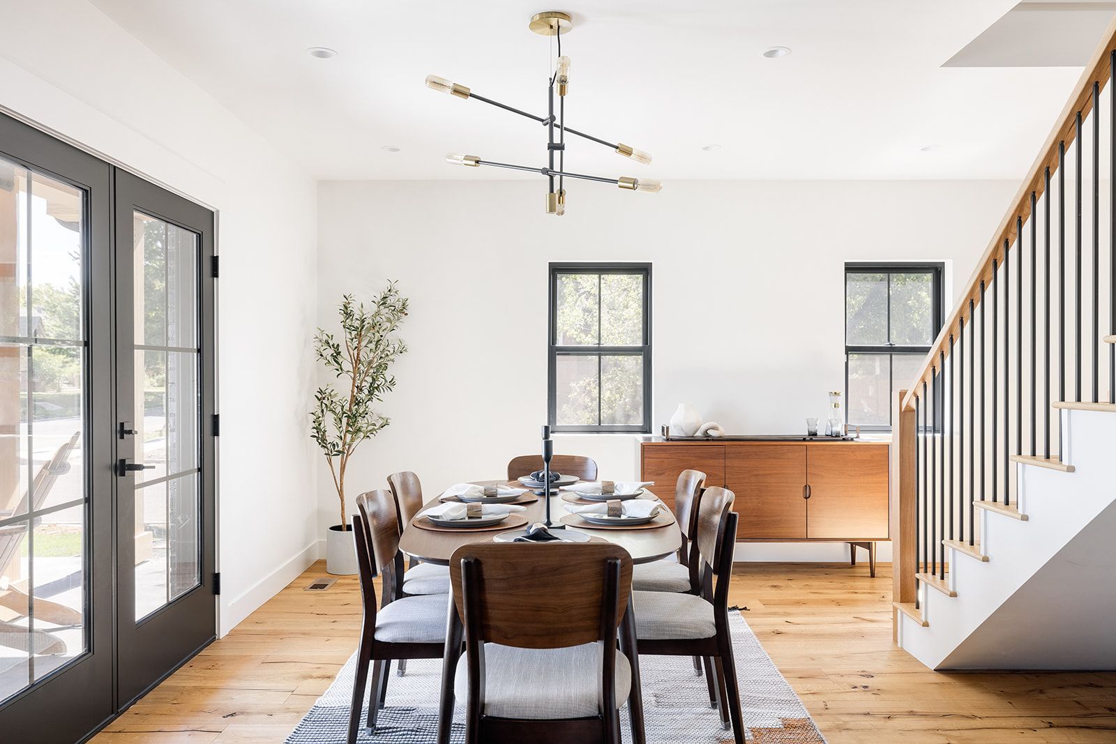 A dining room with a table and chairs and a staircase.
