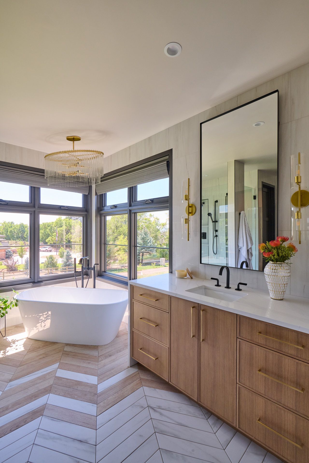 A bathroom with a tub , sink , mirror and large windows.