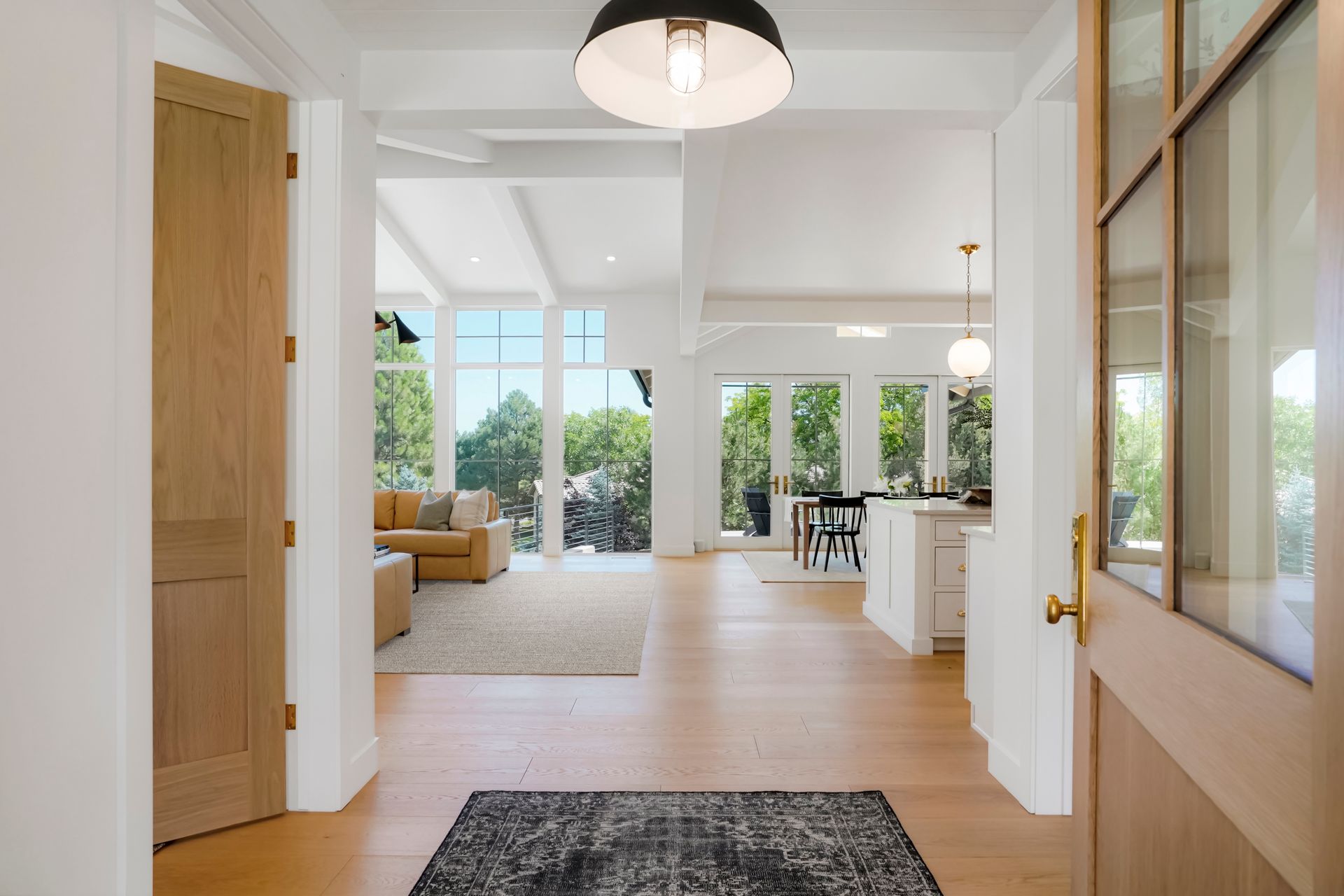 A hallway in a house with a rug on the floor and a lamp hanging from the ceiling.